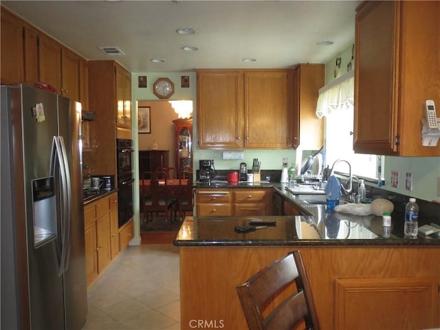 kitchen featuring visible vents, dobule oven black, a sink, a peninsula, and stainless steel fridge with ice dispenser