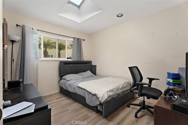 bedroom with a skylight and light wood-type flooring