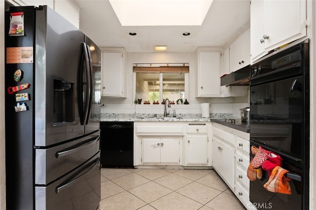 kitchen featuring sink, light tile patterned floors, a skylight, black appliances, and white cabinets