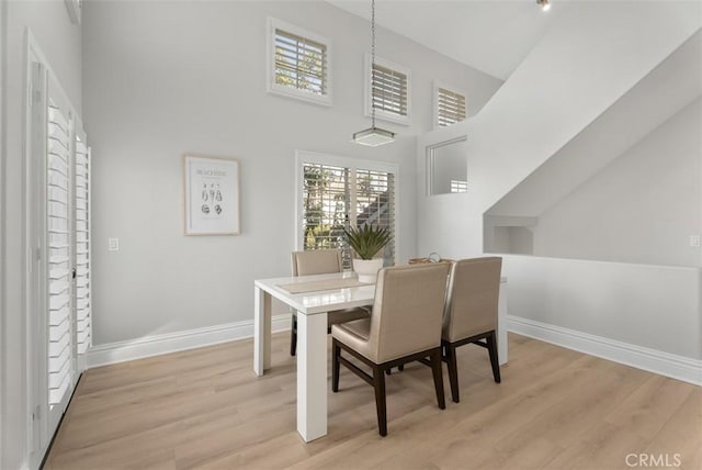 dining room featuring a towering ceiling and light hardwood / wood-style flooring