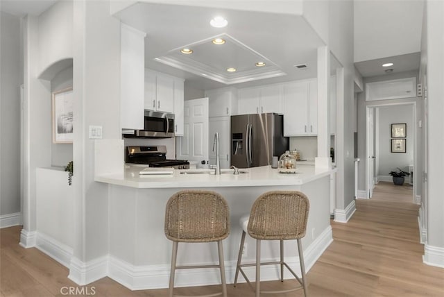 kitchen with white cabinetry, a breakfast bar area, stainless steel appliances, and kitchen peninsula