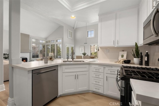 kitchen with appliances with stainless steel finishes, sink, white cabinets, and kitchen peninsula