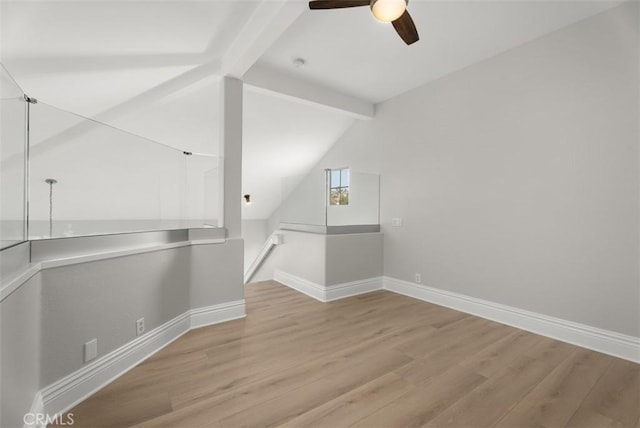 unfurnished room with ceiling fan, light hardwood / wood-style flooring, and vaulted ceiling with beams