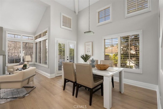 dining space with french doors, high vaulted ceiling, and light hardwood / wood-style flooring