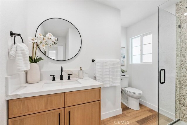 5594 Denver St, Montclair, CA 91763 - bathroom with wood finished floors, toilet, vanity, baseboards, and a stall shower