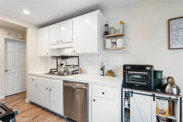 kitchen with tile countertops, open shelves, stainless steel dishwasher, and white cabinetry