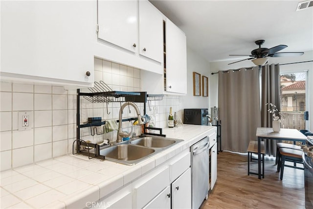 kitchen with visible vents, tile countertops, light wood-type flooring, white cabinetry, and stainless steel dishwasher