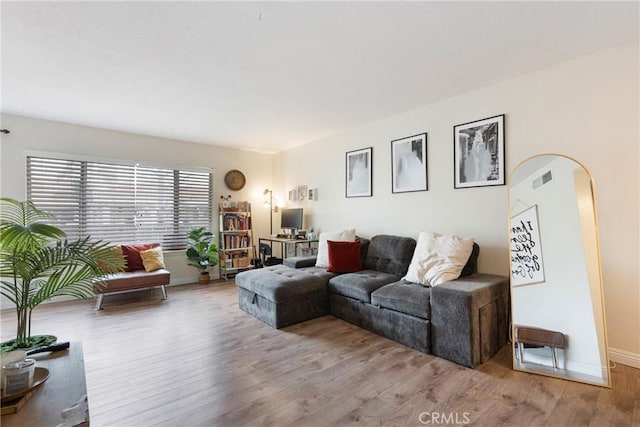 living area featuring light wood-style floors, visible vents, and baseboards