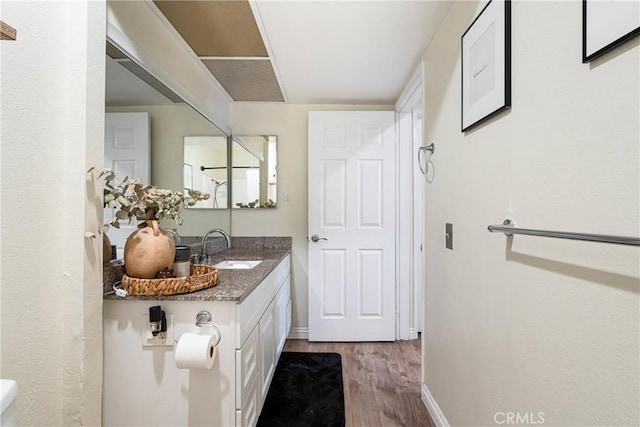 bathroom featuring baseboards, wood finished floors, and vanity