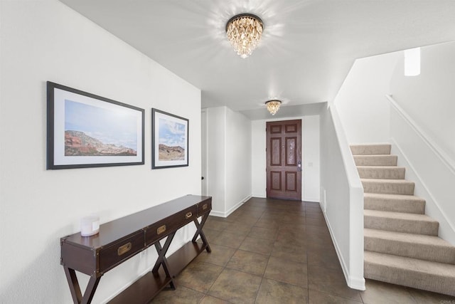 entrance foyer featuring an inviting chandelier and dark tile patterned floors