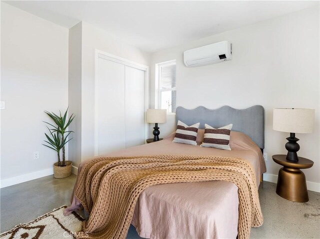 bedroom featuring concrete flooring, a wall mounted air conditioner, and a closet