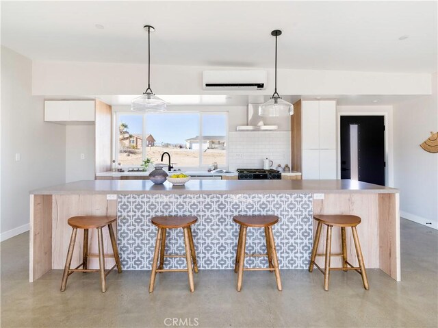 kitchen featuring white cabinetry, pendant lighting, a kitchen island, and an AC wall unit