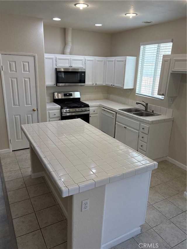 kitchen with stainless steel appliances, tile counters, and white cabinets