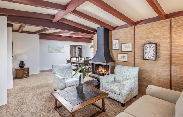 living room with beamed ceiling, carpet, and a wood stove