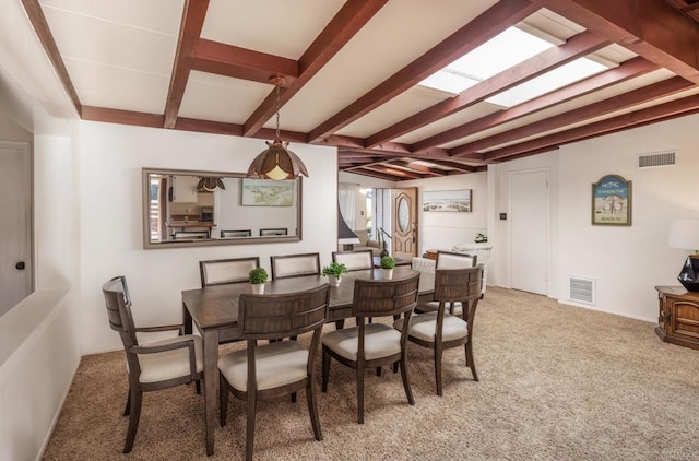 carpeted dining space with beamed ceiling