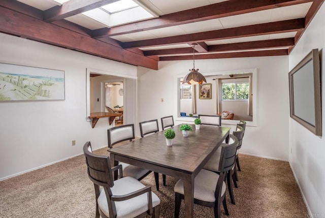 dining space featuring beamed ceiling, carpet flooring, and a skylight