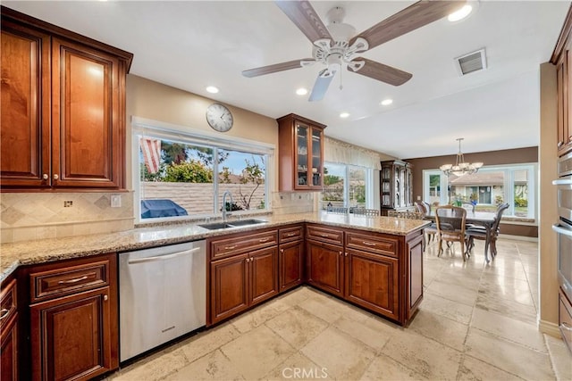 kitchen featuring hanging light fixtures, dishwasher, sink, and light stone counters