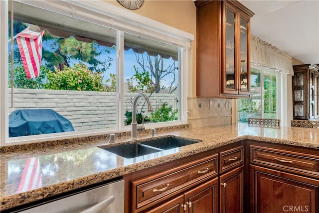 kitchen with tasteful backsplash, dishwasher, sink, and light stone counters