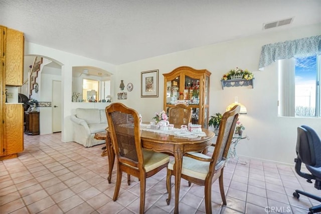 1308 Pleasant Valley Ave, Banning, CA 92220 - dining area with light tile patterned floors, baseboards, visible vents, arched walkways, and a textured ceiling