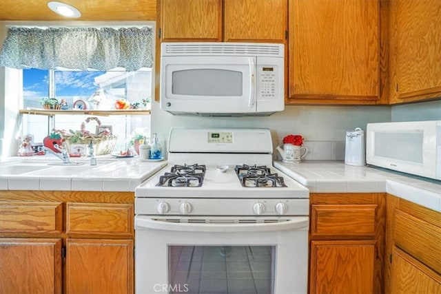 1308 Pleasant Valley Ave, Banning, CA 92220 - kitchen with tile countertops, white appliances, brown cabinetry, and a sink