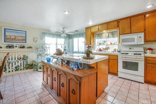 1308 Pleasant Valley Ave, Banning, CA 92220 - kitchen with brown cabinets, white appliances, light countertops, and a kitchen island