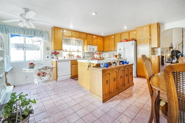 1308 Pleasant Valley Ave, Banning, CA 92220 - kitchen with arched walkways, light tile patterned floors, white appliances, light countertops, and a center island