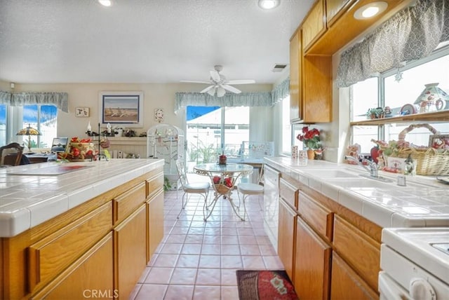 1308 Pleasant Valley Ave, Banning, CA 92220 - kitchen with light tile patterned floors, tile counters, stove, a ceiling fan, and a sink