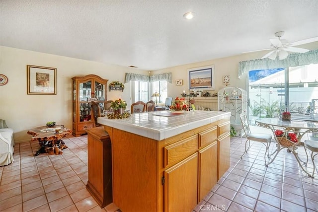 1308 Pleasant Valley Ave, Banning, CA 92220 - kitchen featuring light tile patterned floors, a ceiling fan, tile counters, and brown cabinets