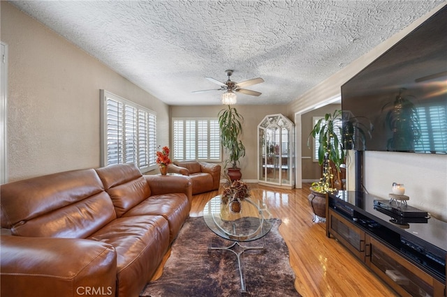 living room featuring a textured ceiling, ceiling fan, and light hardwood / wood-style flooring