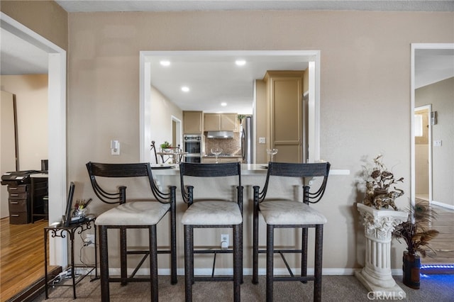 kitchen with oven, stainless steel refrigerator, and light brown cabinets