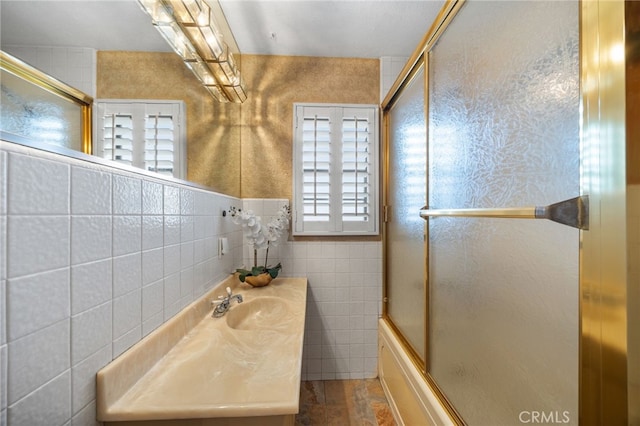 bathroom with tile walls, sink, and enclosed tub / shower combo