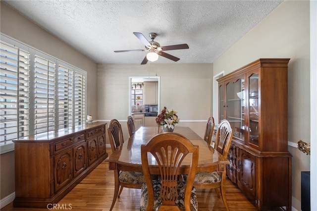 dining room featuring hardwood / wood-style flooring, ceiling fan, and a textured ceiling