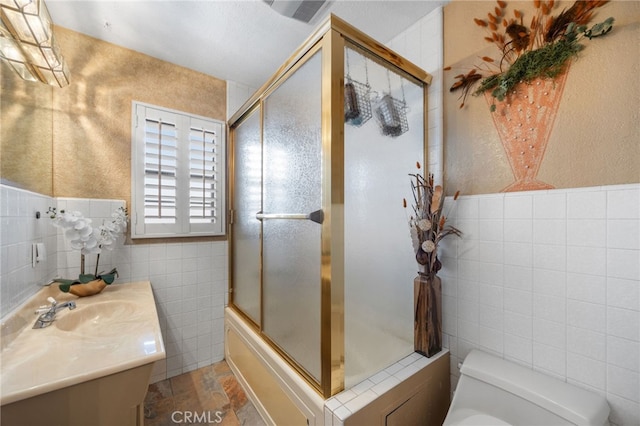 full bathroom featuring vanity, tile walls, shower / bath combination with glass door, and toilet