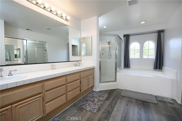 bathroom featuring hardwood / wood-style flooring, plus walk in shower, vanity, and backsplash