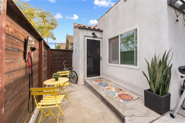 exterior space featuring a patio, fence, a tile roof, and stucco siding
