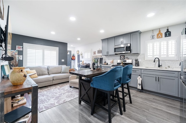 2324 E 14th St, Long Beach, CA 90804 - kitchen with gray cabinets, a sink, stainless steel microwave, backsplash, and plenty of natural light