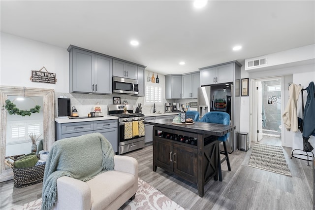 kitchen featuring gray cabinetry, appliances with stainless steel finishes, and light wood finished floors