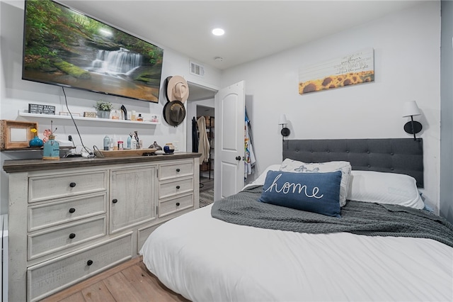 bedroom with light wood-style floors and visible vents