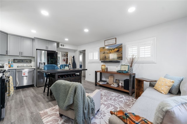 living room with recessed lighting, visible vents, and light wood-style floors