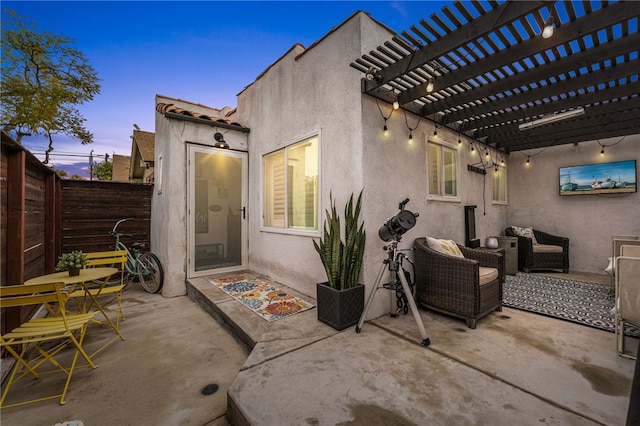 back of property at dusk with a fenced backyard, a patio area, stucco siding, and a pergola