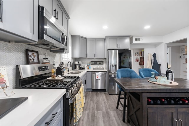 kitchen featuring gray cabinets, visible vents, light wood-type flooring, a sink, and stainless steel appliances