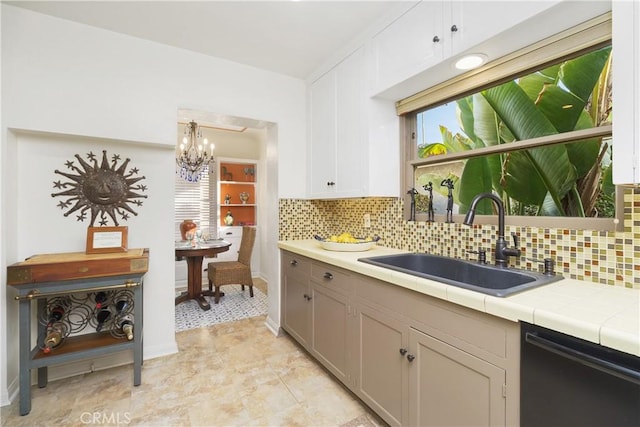 kitchen featuring white cabinetry, dishwasher, sink, backsplash, and tile counters