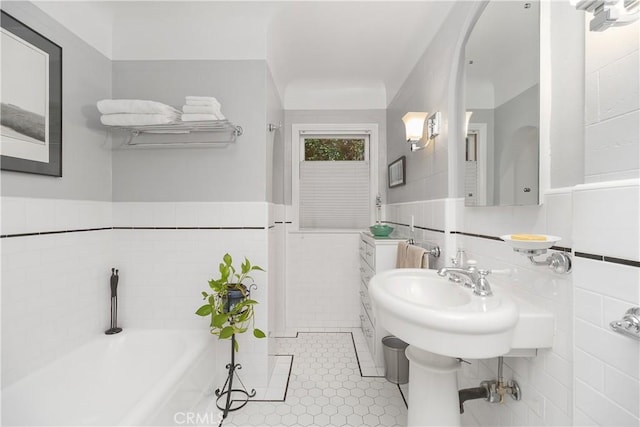 bathroom featuring tile walls, tile patterned floors, and a tub to relax in