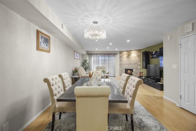 dining space with a notable chandelier, hardwood / wood-style flooring, and a large fireplace