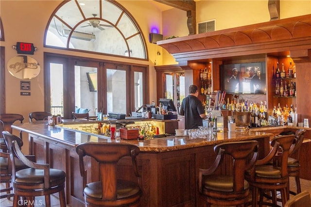 bar featuring a high ceiling, ceiling fan, and french doors