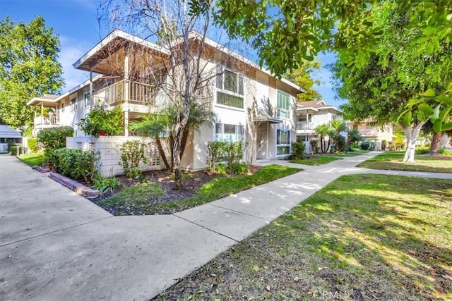 view of front of home with a balcony and a front yard