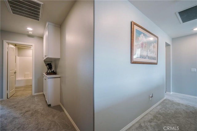 corridor with light carpet, recessed lighting, visible vents, and baseboards