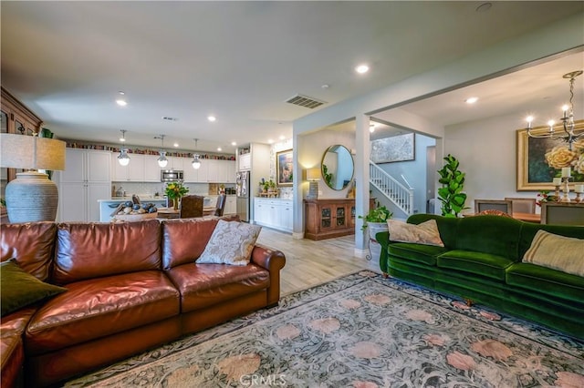 living room with recessed lighting, visible vents, light wood-style floors, stairway, and an inviting chandelier