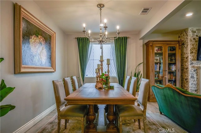 dining space featuring a notable chandelier, baseboards, visible vents, and wood finished floors