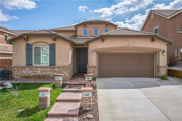 mediterranean / spanish house with stone siding, an attached garage, concrete driveway, and stucco siding